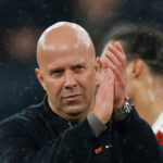 Άρνε Σλοτ στον πάγκο της Λίβερπουλ με το έμβλημα στο φόντο